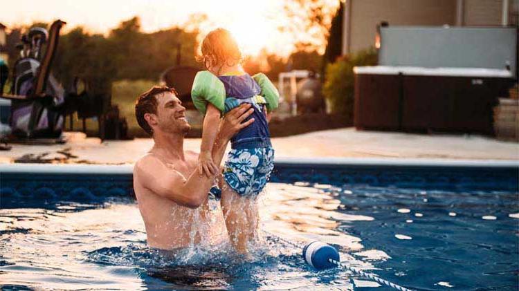 Dad lifting child in swimming pool.