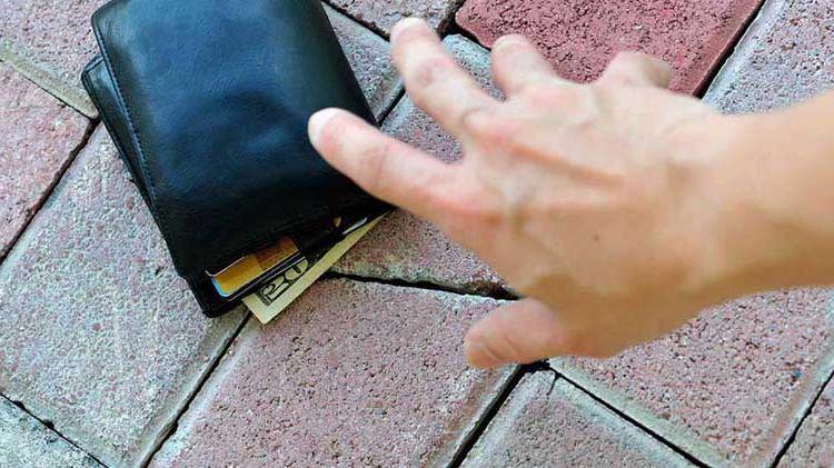 Hand reaching for wallet on ground.