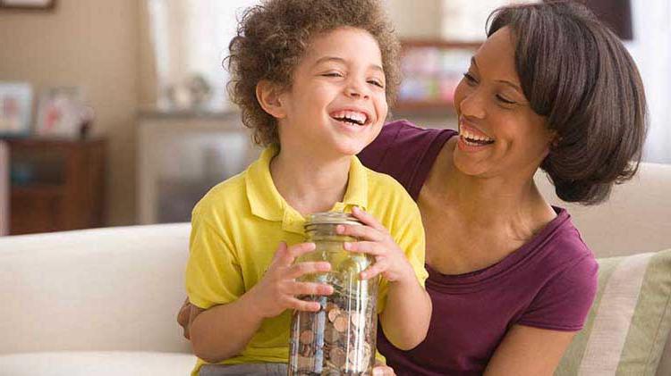 Mother with young boy holding jar with coins.